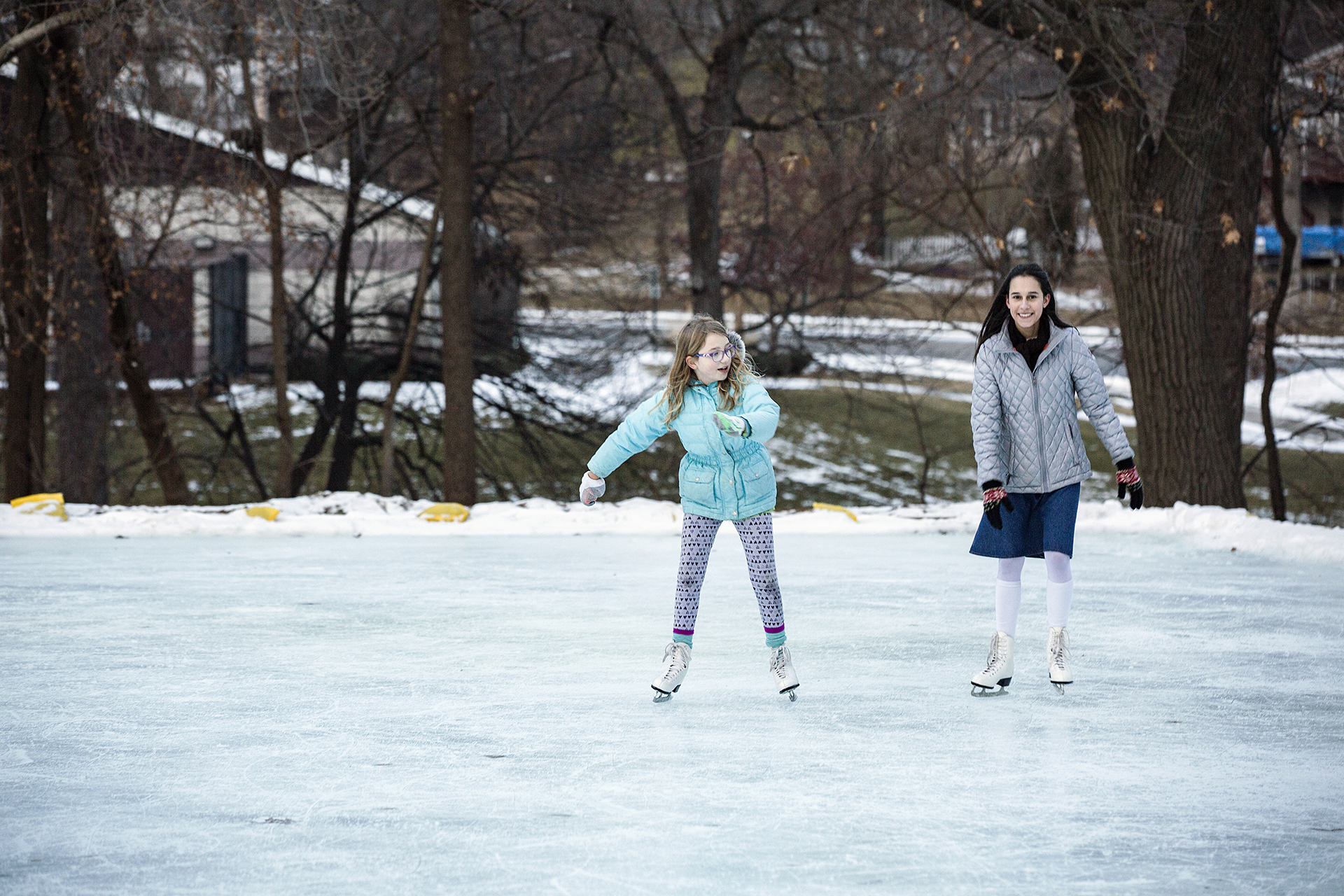 two girls ice skating outdoors during winter in cedar rapids